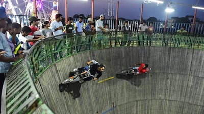 Stuntmen ride their motorbikes along the wall of a wooden structure during the 'Wall of Death' show at a fair in Jalandhar. AFP