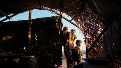 Children stand in front of their traditional reed house in the Chebayesh marshes, Nasiriyah, Iraq.  AP Photo