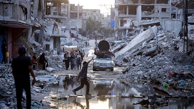 Palestinians displaced by the Israeli air and ground offensives, walk past sewage flowing into the streets of Khan Younis. Health authorities and aid agencies are attempting to avert an outbreak of polio in the enclave. AP
