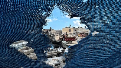 Palestinians, seen through a torn tent, ride a vehicle past the rubble, amid the Israel-Gaza war, in Khan Younis. Reuters