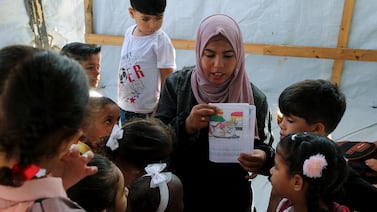 Israa Abu Mustafa teaches students inside a tent set up on the rubble of her house in Khan Younis, in the southern Gaza Strip. Reuters