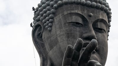 Two cleaners work on the right ear of the Ushiku Daibutsu giant Buddha statue in Ushiku, Japan. AFP