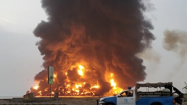 A Houthi police car drives past fire and smoke following Israeli air strikes in Hodeidah, Yemen, on July 20. EPA