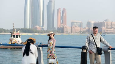 Tourists taking photos with the Abu Dhabi skyline in the background. Passenger traffic at the country's airports rose by more than 14 per cent in the first half of this year. Khushnum Bhandari / The National