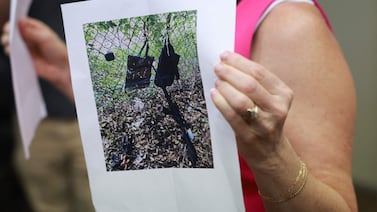 A Palm Beach County Sheriff's official holds a photograph of the rifle and other items found near where the suspect was discovered. Getty / AFP