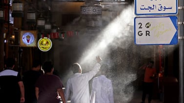 People walk through a mist dispenser as they enter al-Mubarakiya market amid high temperatures in Kuwait City. AFP